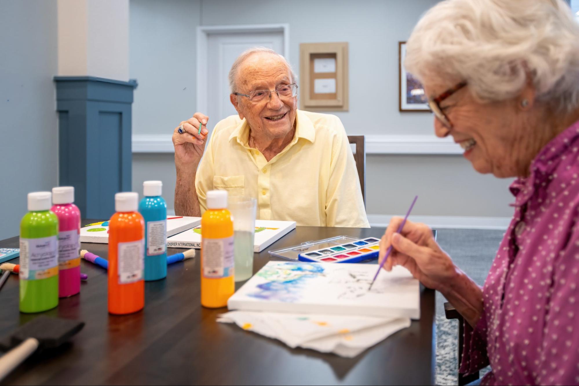 Two senior residents at High Plains Crossing enjoy painting with watercolors on canvas.