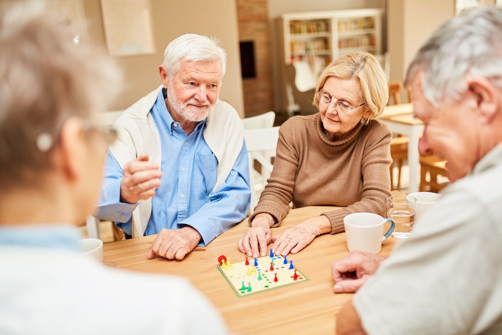 A pair of older adults relaxing while playing board games and sharing a warm smile.